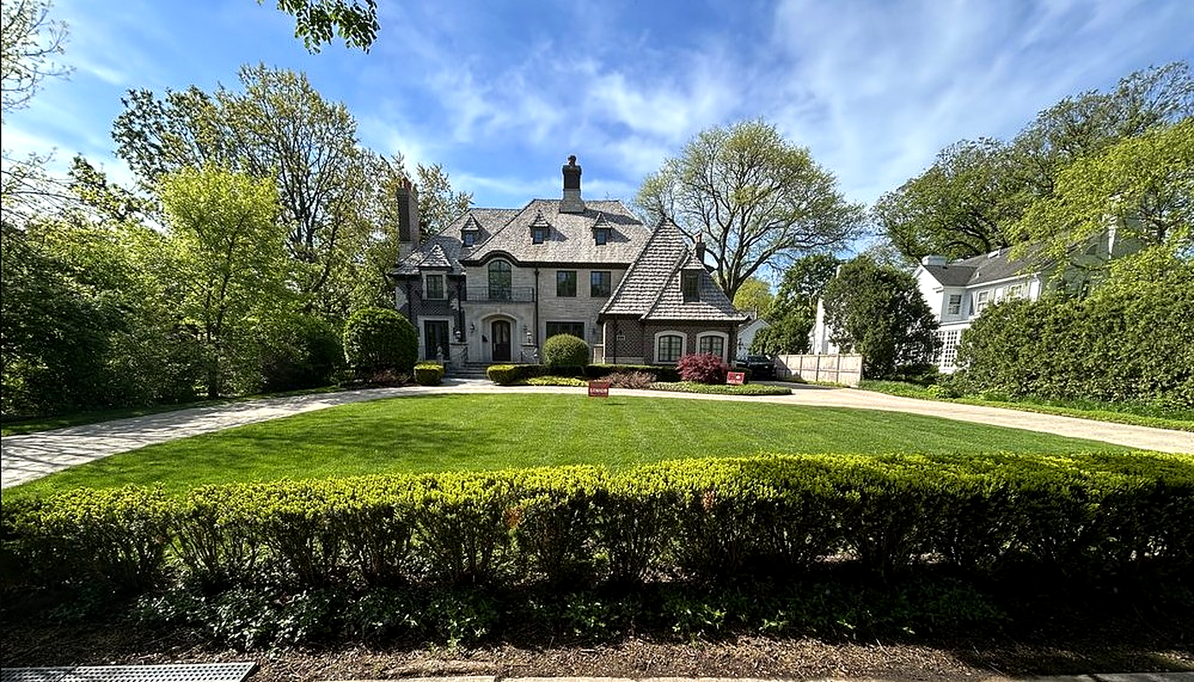 Deep front lawn framed by mature trees