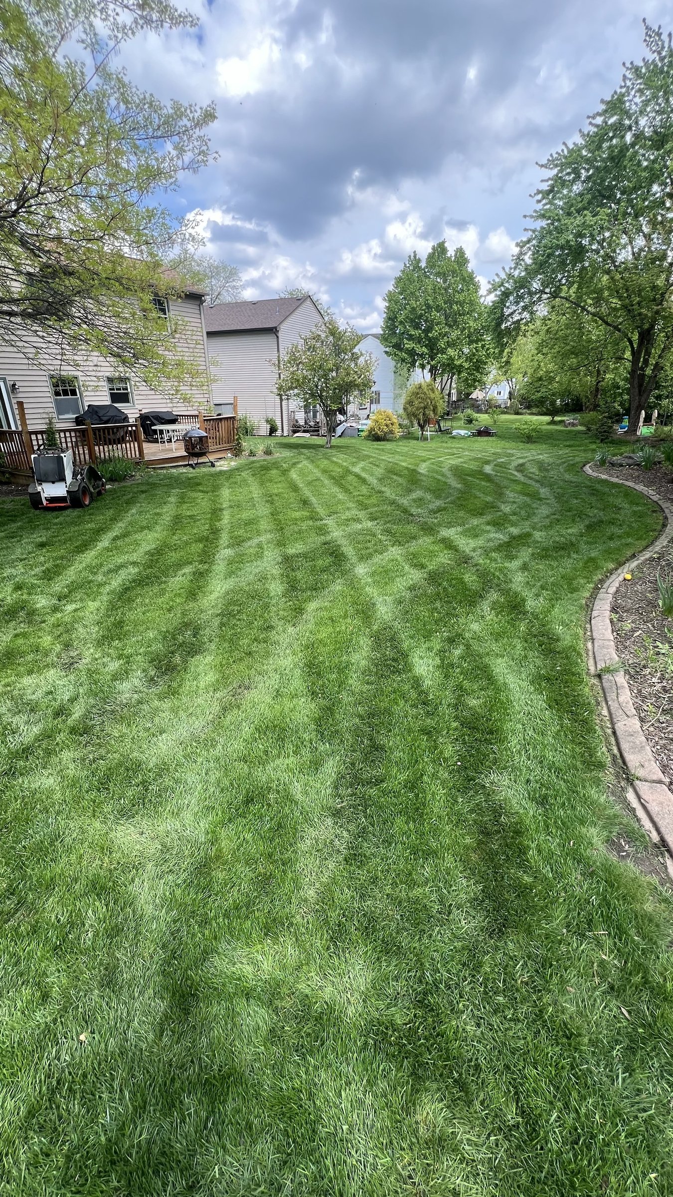 Striped backyard lawn beside a wood deck