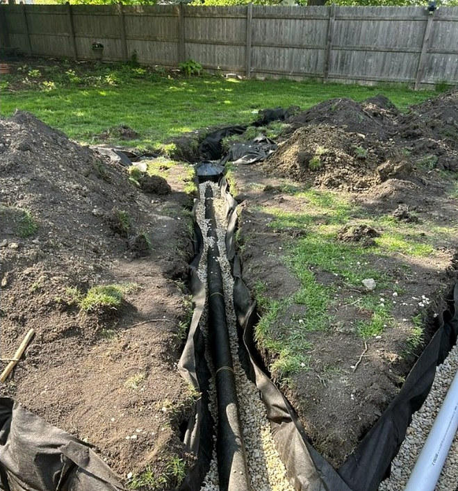 Drainage trench with pipe, gravel, and fabric during installation