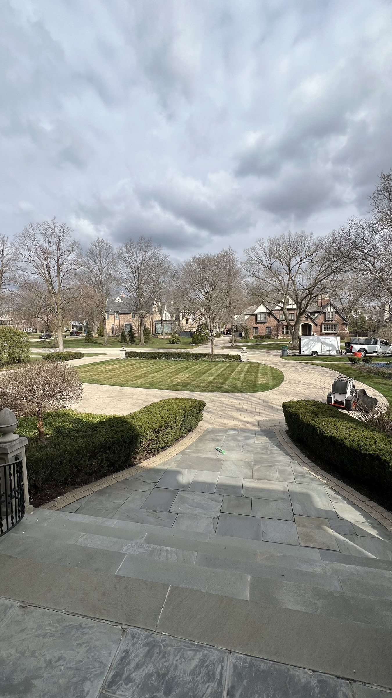 Bluestone steps leading to a circular striped lawn and paver drive