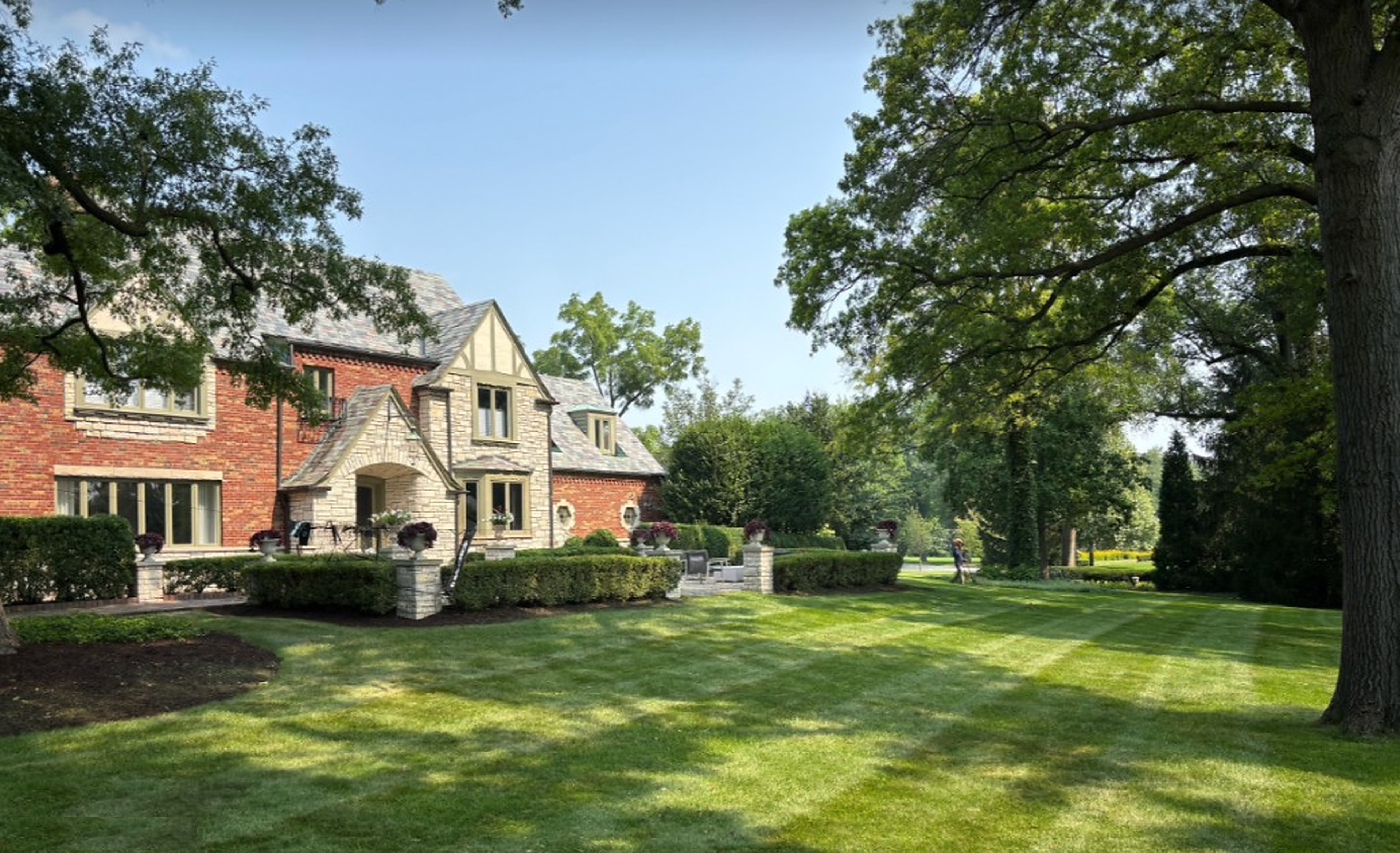 Striped lawn and formal hedges at a brick-and-stone estate