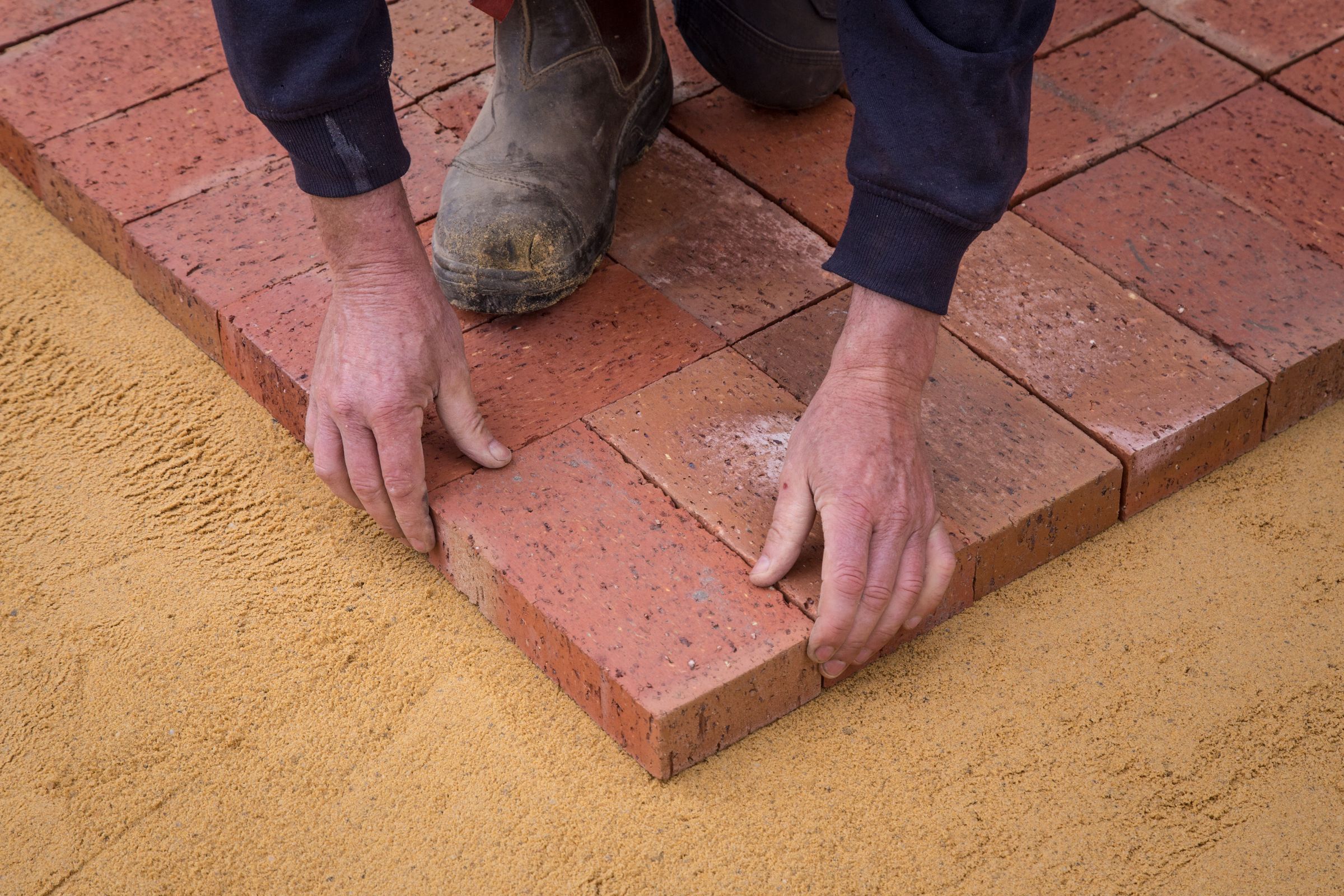 Mason laying brick in a running bond